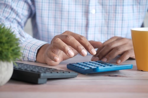 Photo of hands typing on calculator