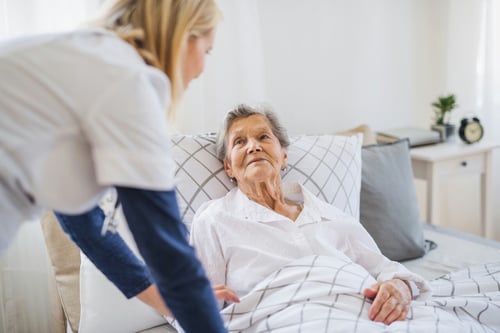 Nurse taking care of patient in a bed