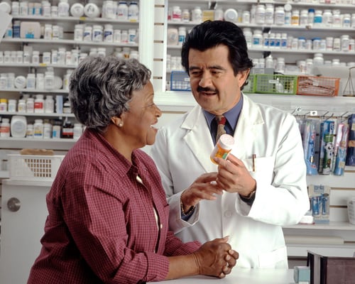 senior discussing medicare prescription deductible with pharmacist at pharmacy