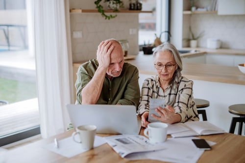 Older couple looking at laptop and papers on desk