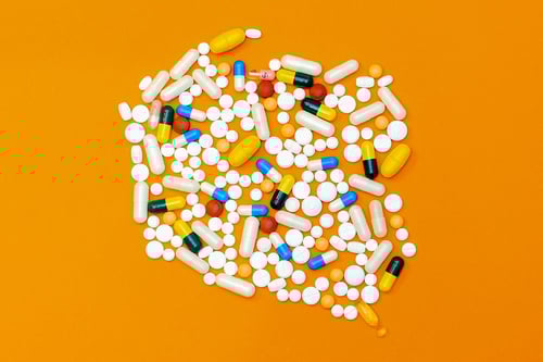 various sized prescription pills on orange background