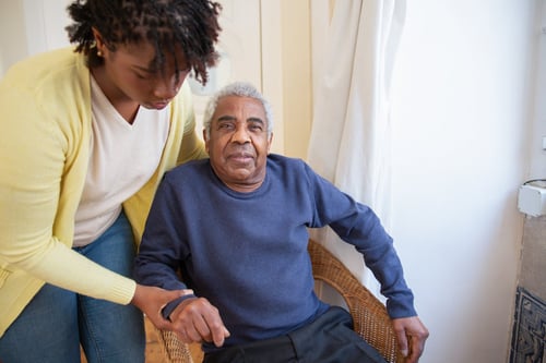 Man in wheelchair being helped by caregiver