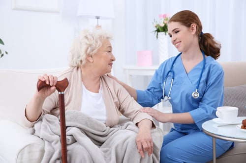 longterm care nurse talking with elderly woman holding a cane