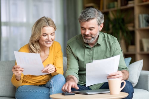 middle age couple reviewing important life insurance documentation together while sitting in living room