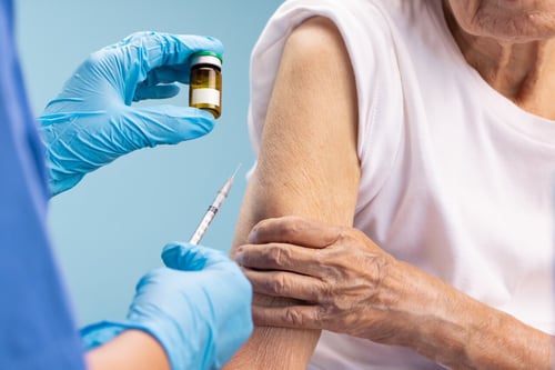 Senior woman receiving shingles vaccine from nurse