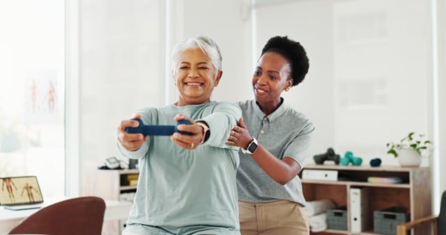 a senior woman with short white hair holding a weight performing physical therapy with a physical therapist