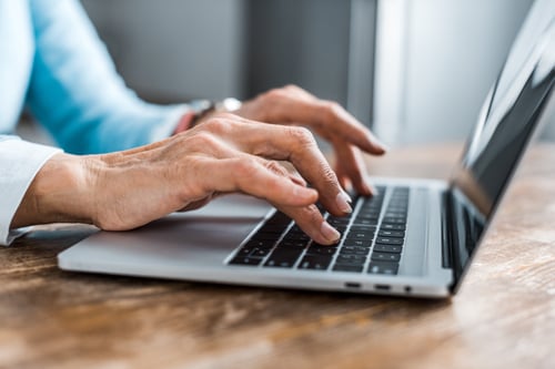 close up of elderly woman typing on a laptop