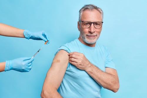 older adult in blue shirt getting a vaccine