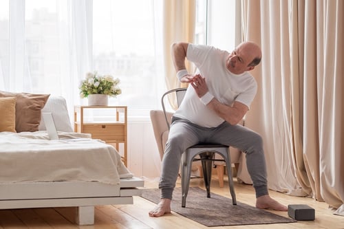 man doing chair yoga exercises indoors