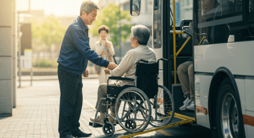 a senior man helping an elderly woman in a wheelchair get onto a public bus transportation