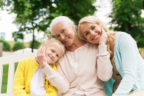 woman with aging parent and daughter sitting outdoors in park