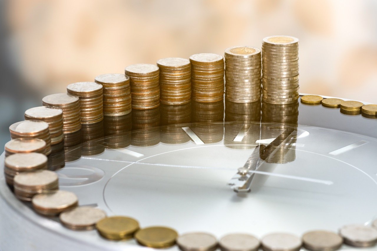 Stacks of coins increasing in height on top of a clock, representing annuity growth and time-based financial planning.