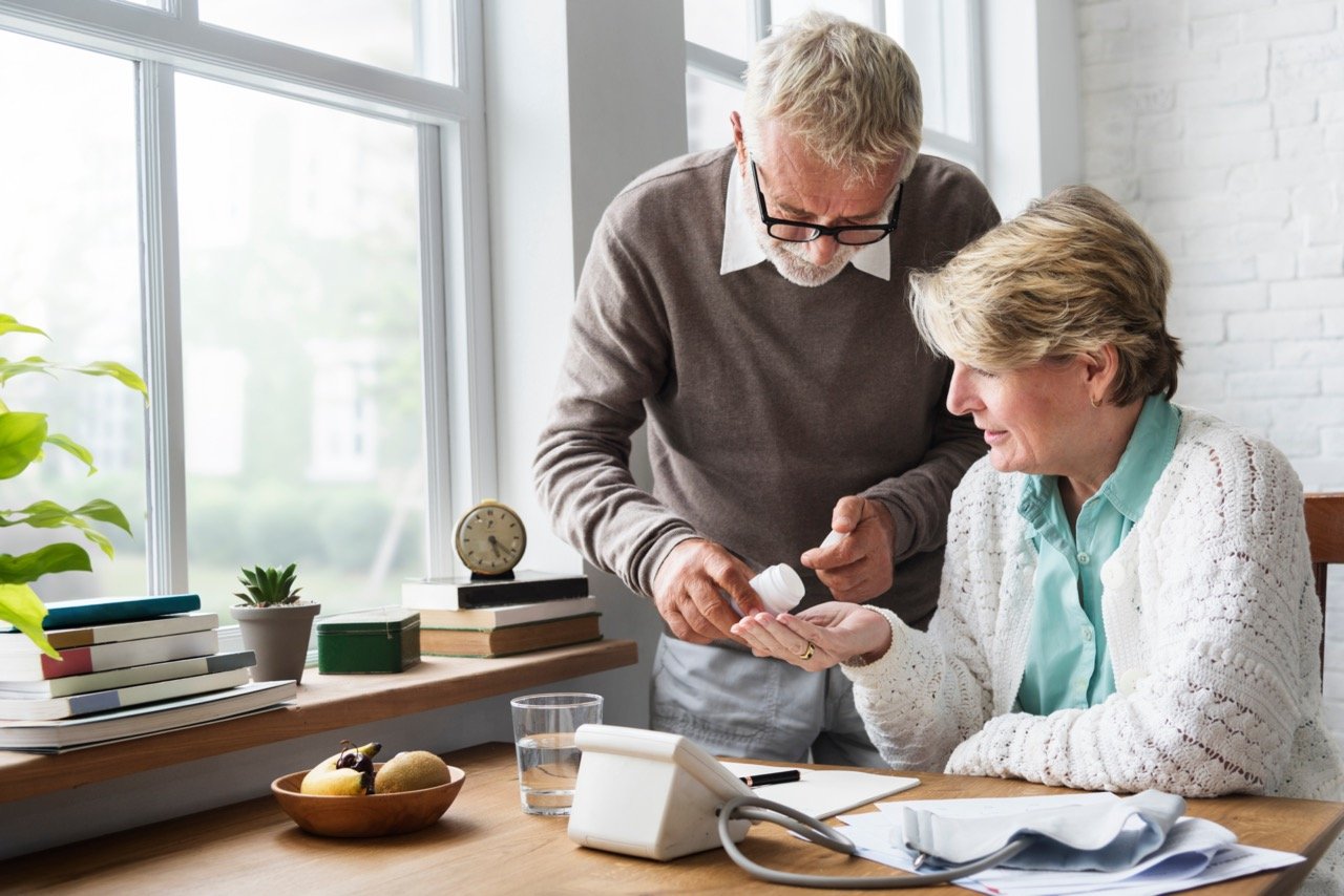 senior couple in kitchen checking prescription medication