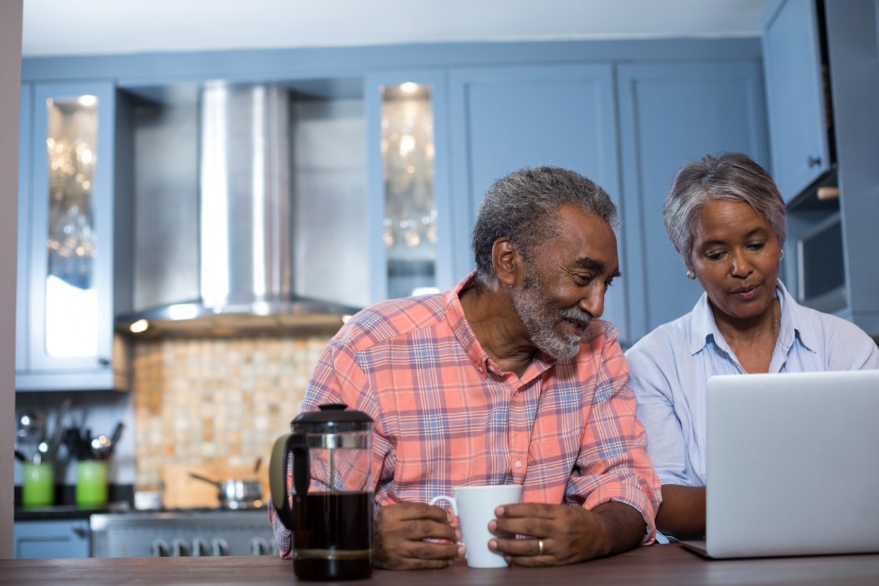 senior couple sitting at kitchen counter looking at medicare information on a laptop screen