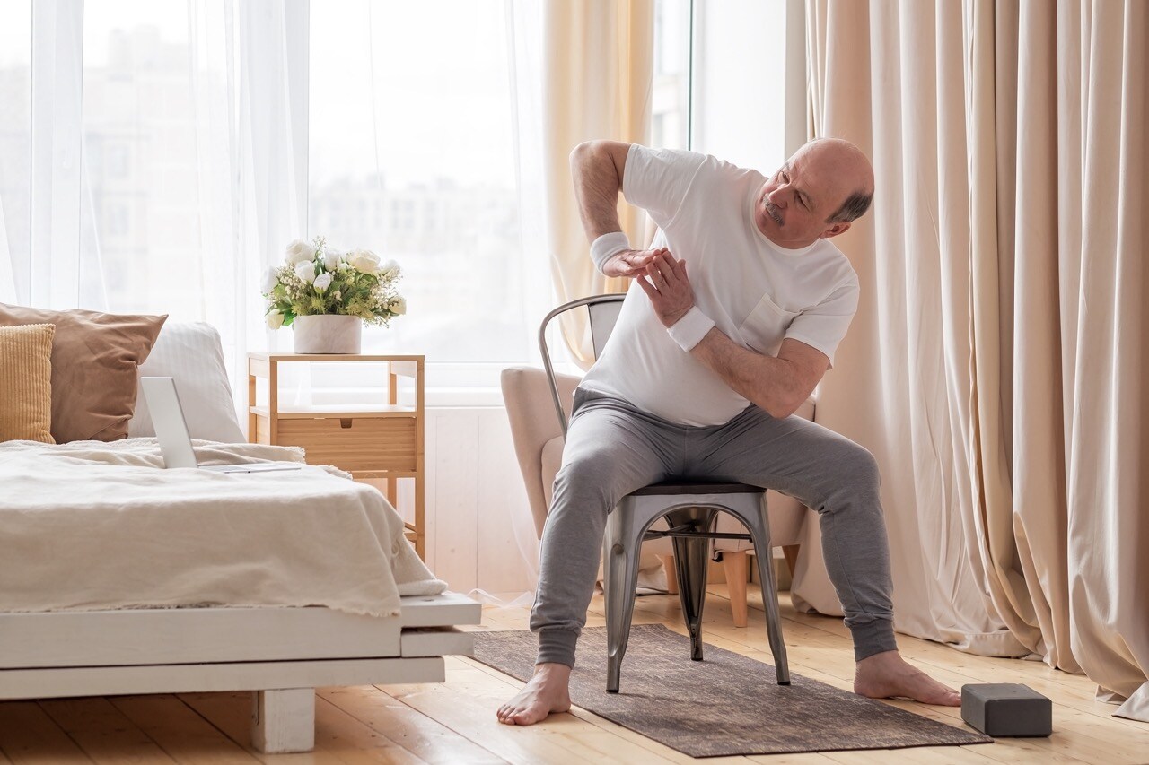 man doing chair yoga exercises indoors